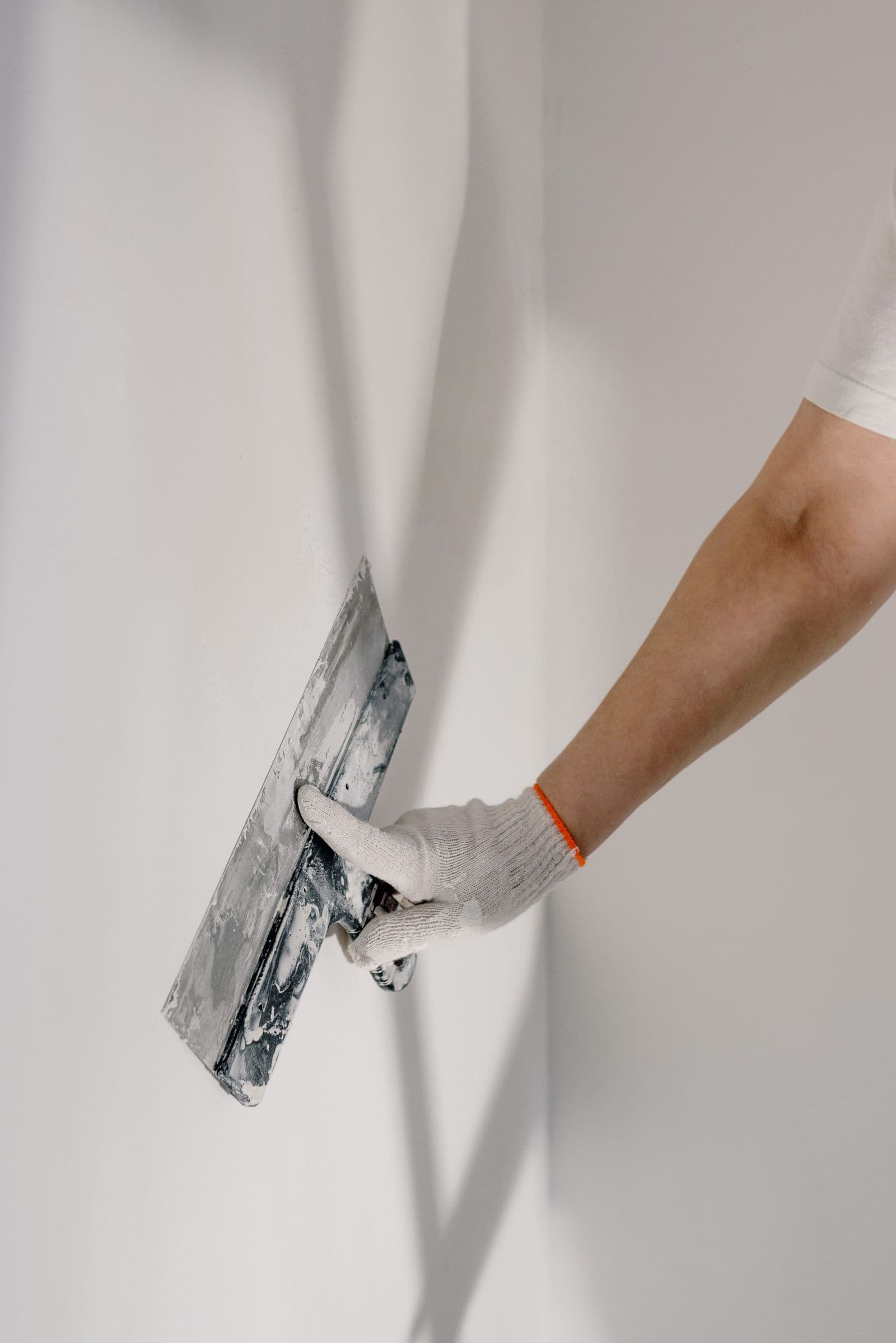 Gloved hand working a wall smooth with a trowel