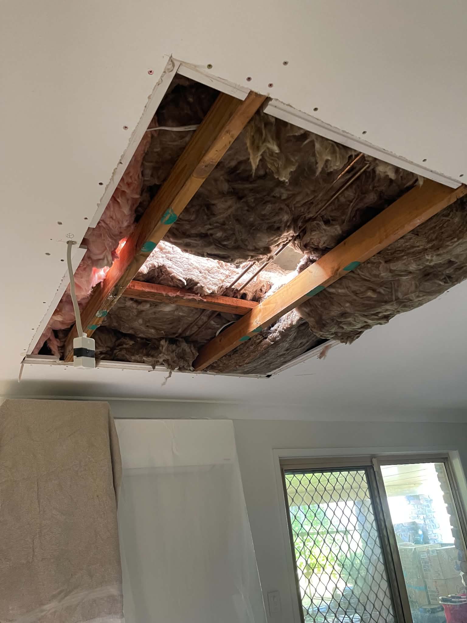 Ceiling cut-away showing joists and insulation before the patch is reinstated